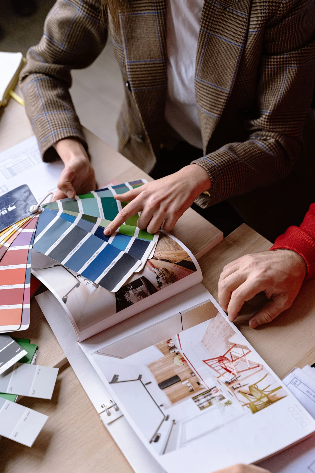 Hands comparing colour swatches and references around a table
