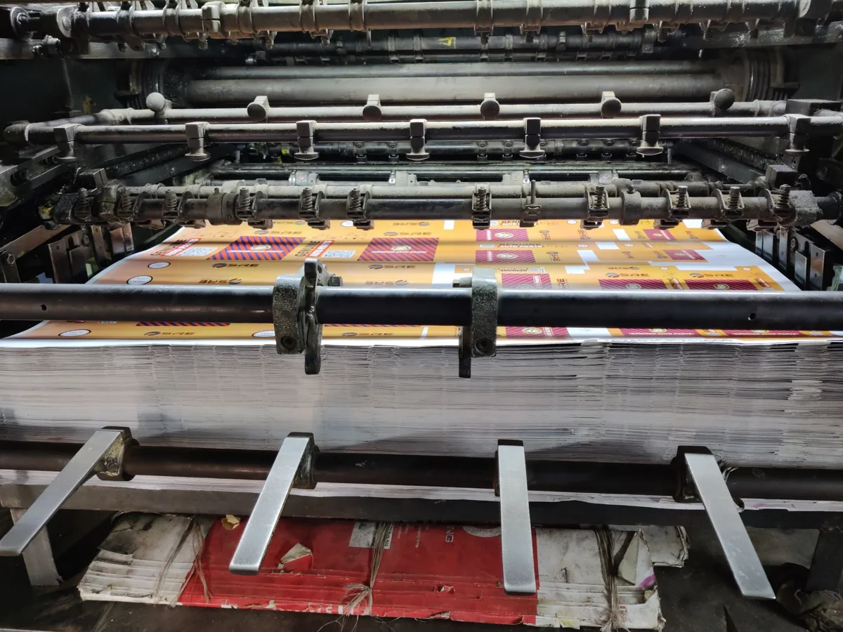 Printed sheets moving through the rollers of a production press